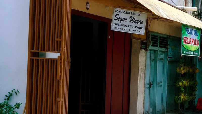 Pintu masuk Toko Obat Segar Waras di Jalan Hasanudin No. 61, Pekalongan, dengan papan nama bertuliskan Toko Obat Berijin Segar Waras.